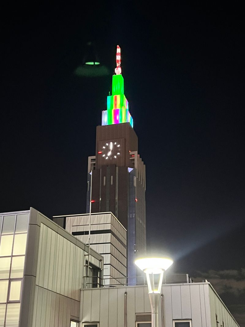 A city tower glowing green and red against the night sky