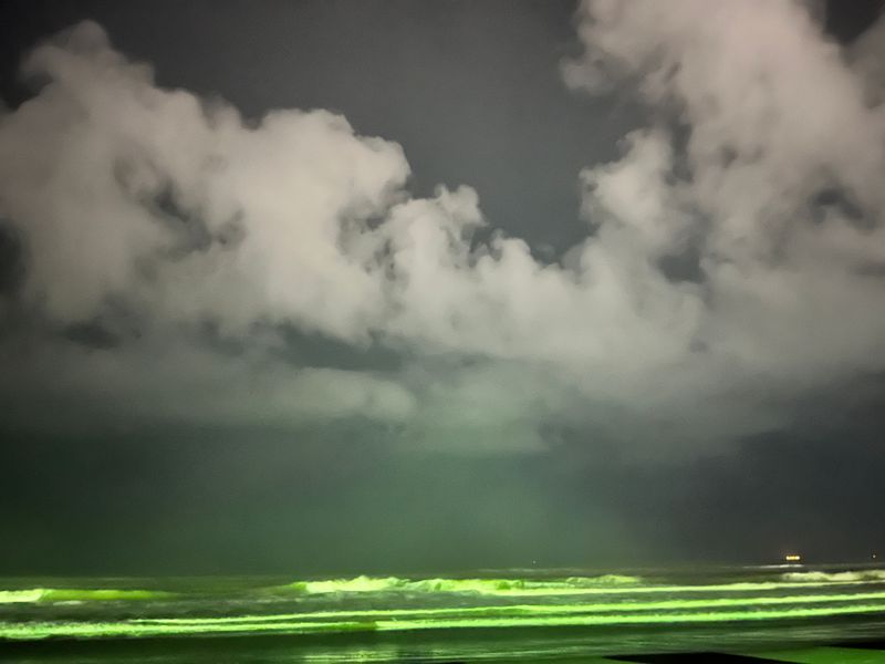 Dramatic clouds gathering over a green-lit horizon