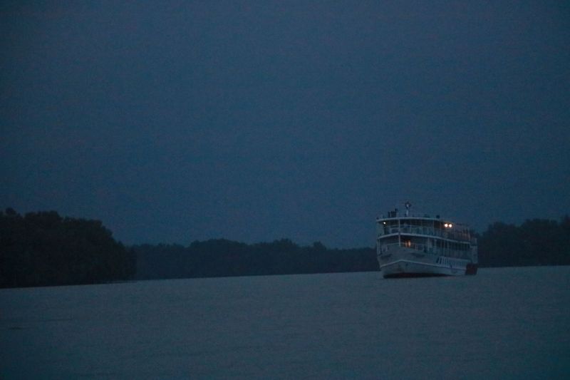 A riverboat with cabin lights on gliding through water at night